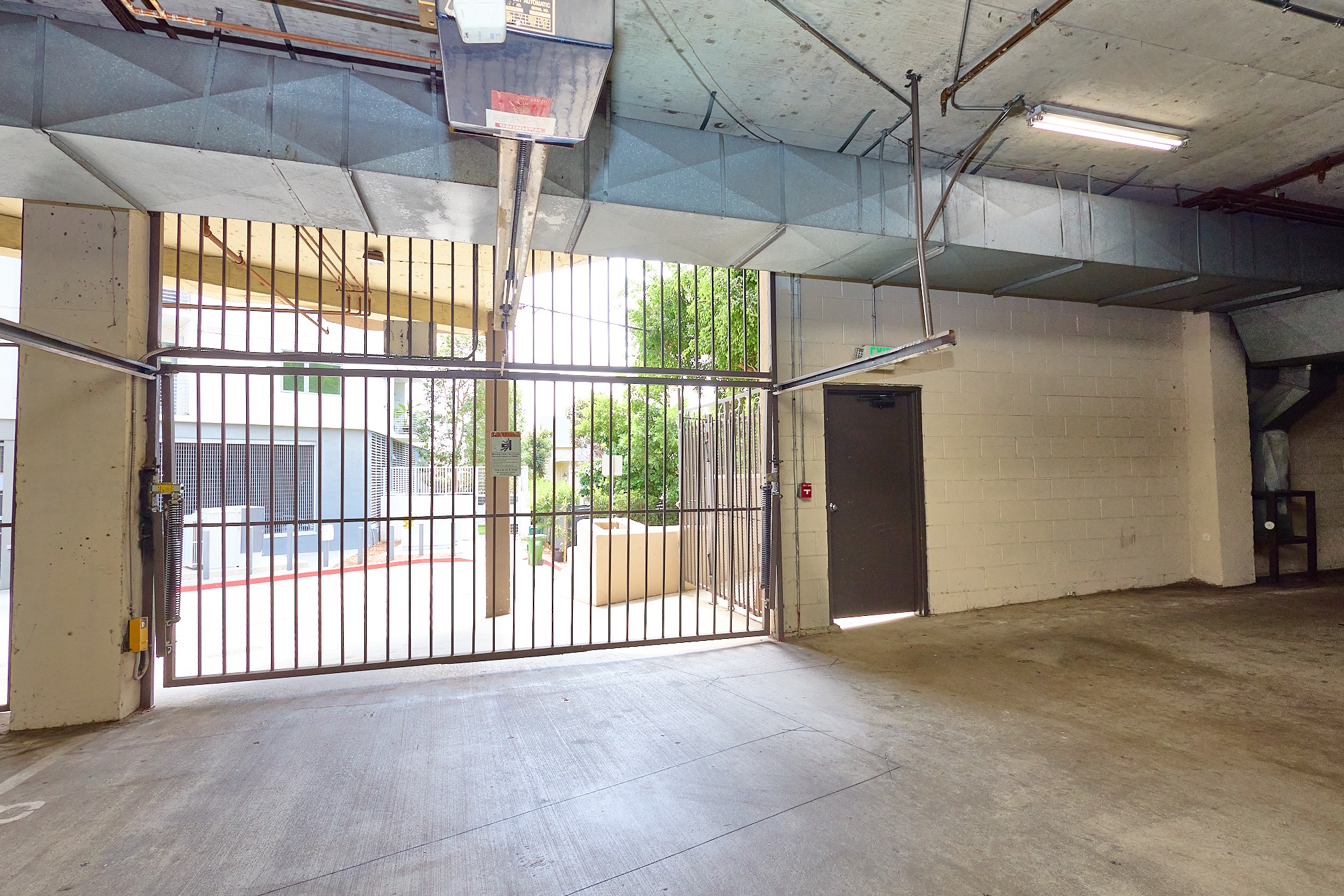 A large, empty garage with a basketball hoop and a basketball on the ground.